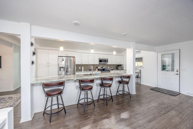 kitchen featuring kitchen peninsula, white cabinetry, stainless steel appliances, and dark wood-type flooring