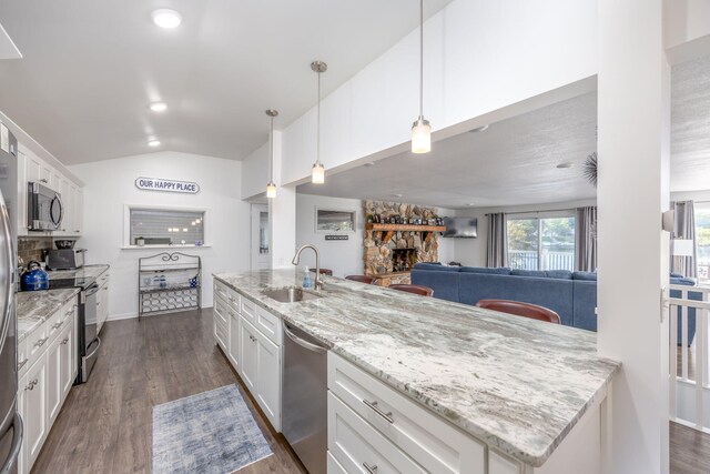 kitchen with white cabinetry, a fireplace, decorative light fixtures, and appliances with stainless steel finishes