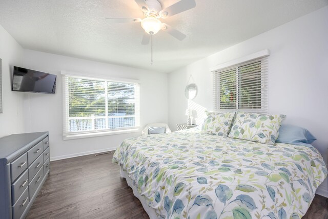 bedroom with a textured ceiling, ceiling fan, and dark wood-type flooring