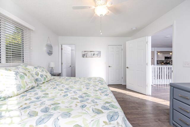 bedroom with ceiling fan, dark wood-type flooring, and a textured ceiling