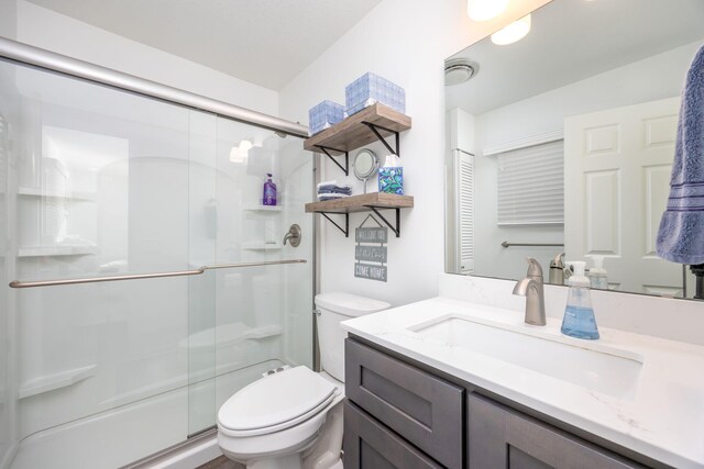 bathroom featuring vanity, an enclosed shower, and toilet