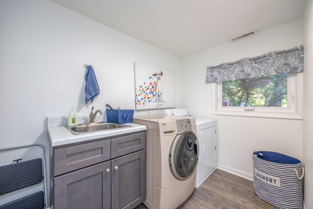 washroom with dark hardwood / wood-style flooring, cabinets, sink, and washing machine and dryer