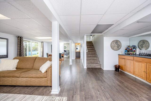 living room with dark hardwood / wood-style flooring and a paneled ceiling