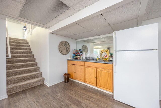 bar featuring a drop ceiling, white fridge, dark wood-type flooring, and sink