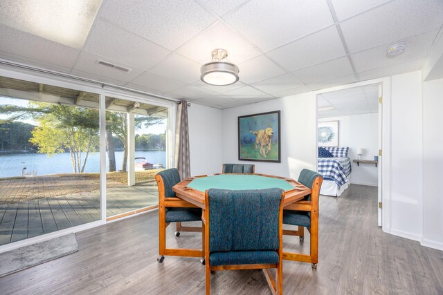 dining room featuring a drop ceiling, a water view, and hardwood / wood-style flooring