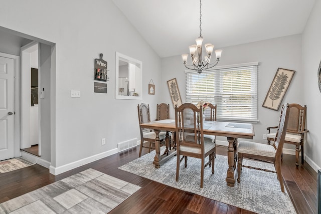 dining space featuring dark wood-type flooring, vaulted ceiling, and an inviting chandelier