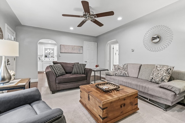 living room with ceiling fan with notable chandelier and light hardwood / wood-style flooring