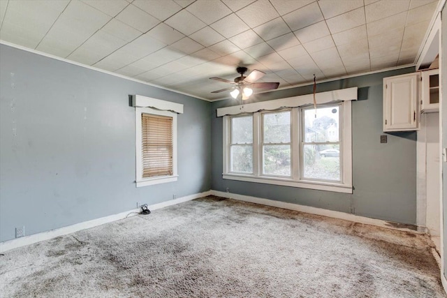 empty room with carpet flooring, ceiling fan, and ornamental molding