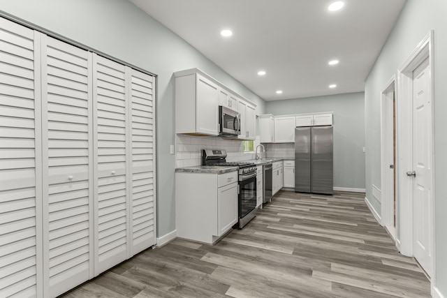 kitchen featuring white cabinets, sink, decorative backsplash, light stone countertops, and stainless steel appliances