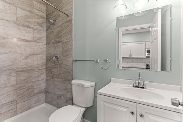 bathroom featuring vanity, toilet, and a tile shower