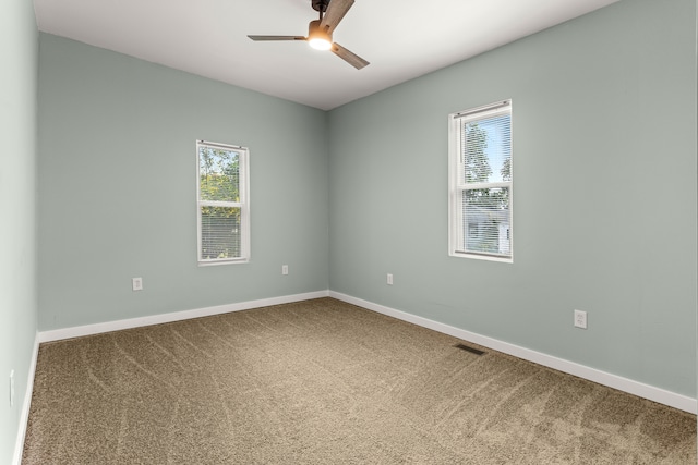 spare room featuring ceiling fan, plenty of natural light, and carpet