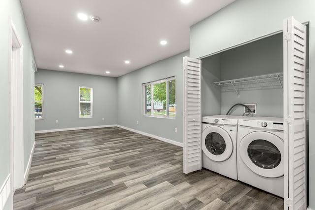 laundry area with washing machine and clothes dryer and hardwood / wood-style flooring