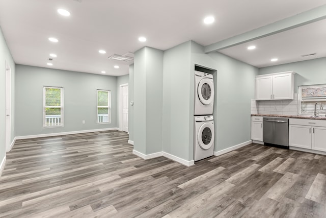 laundry room featuring sink, wood-type flooring, and stacked washer / dryer