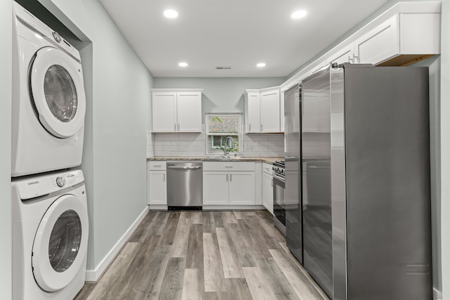 washroom with light wood-type flooring, stacked washer and clothes dryer, and sink