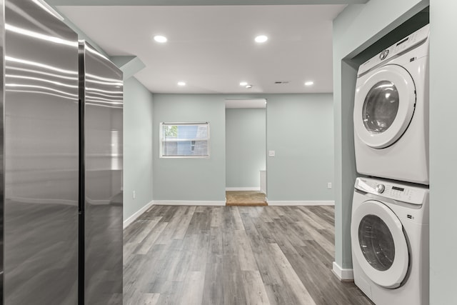 laundry room featuring hardwood / wood-style floors and stacked washer and clothes dryer