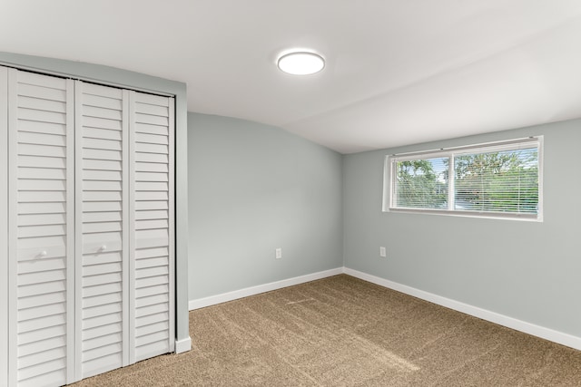 unfurnished bedroom with carpet flooring, vaulted ceiling, and a closet