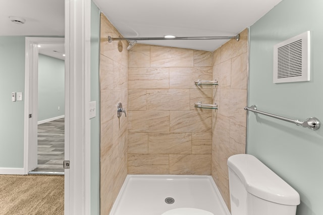 bathroom featuring tiled shower, wood-type flooring, and toilet