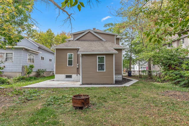 rear view of property featuring a yard, a patio, and an outdoor fire pit