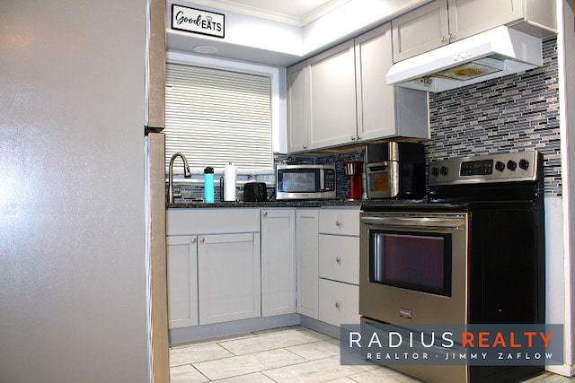 kitchen with tasteful backsplash, ornamental molding, stainless steel appliances, dark stone countertops, and white cabinets