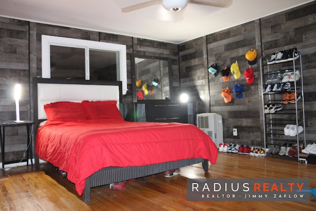 bedroom featuring hardwood / wood-style flooring, ceiling fan, and wooden walls