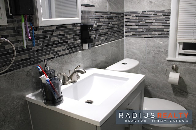 bathroom with decorative backsplash, vanity, toilet, and tile walls