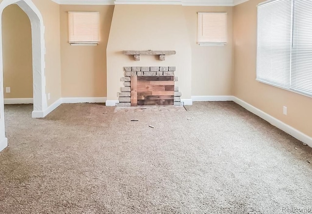 unfurnished living room with a fireplace, carpet floors, and ornamental molding