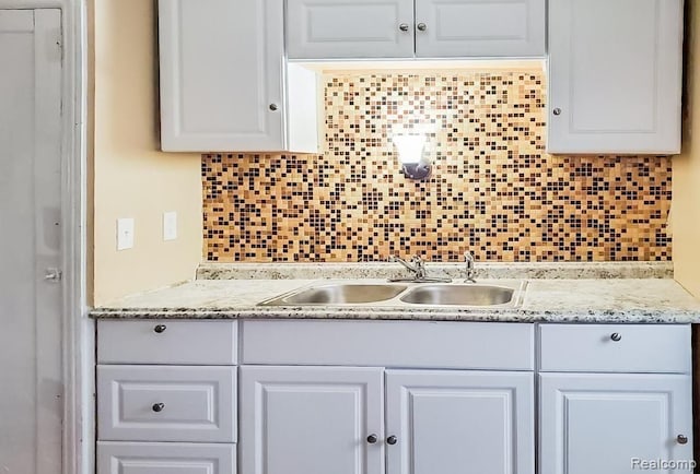 kitchen featuring white cabinets, sink, and tasteful backsplash