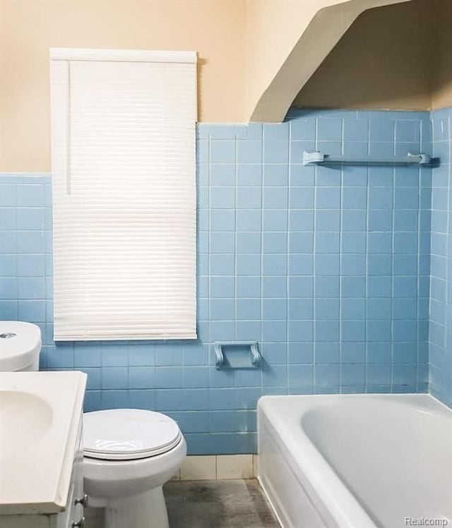 bathroom with vanity, tile walls, and a bathing tub