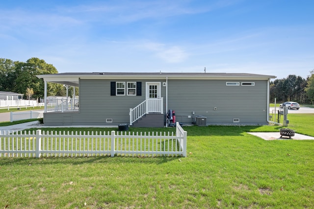 view of front of home featuring a front lawn, central AC unit, and an outdoor fire pit