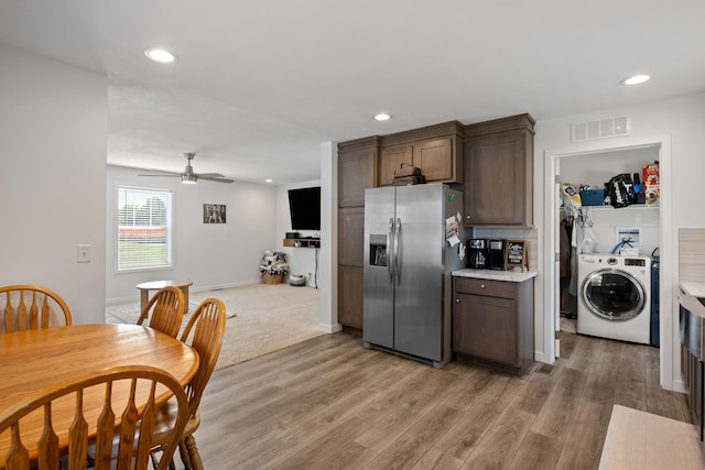 kitchen with dark brown cabinetry, ceiling fan, stainless steel fridge with ice dispenser, washer / clothes dryer, and light wood-type flooring