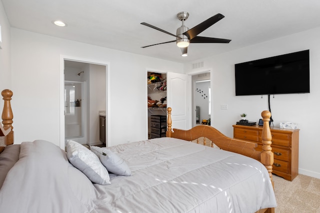 carpeted bedroom featuring a closet, a spacious closet, ensuite bath, and ceiling fan