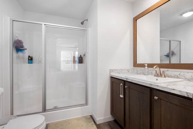 bathroom with hardwood / wood-style floors, vanity, toilet, and a shower with door