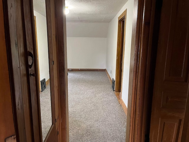 hall with carpet, a textured ceiling, and vaulted ceiling