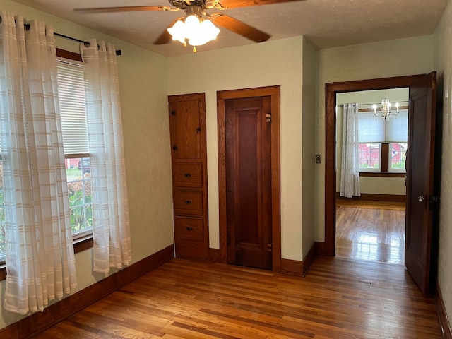 unfurnished bedroom featuring wood-type flooring and ceiling fan with notable chandelier