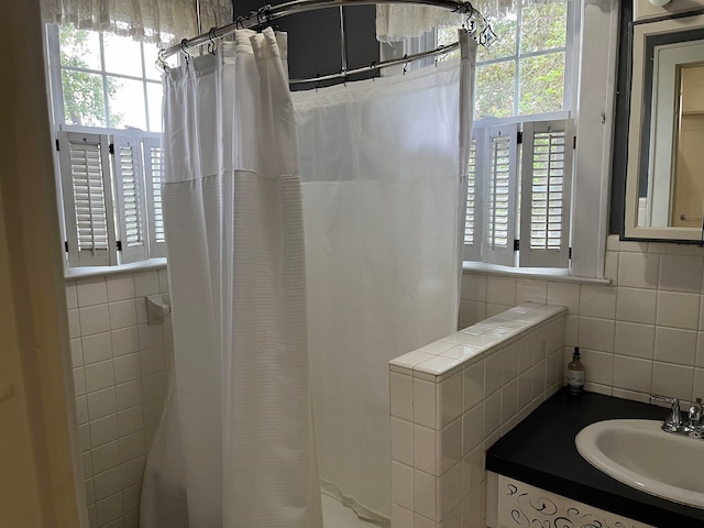 bathroom featuring tile walls, curtained shower, and sink