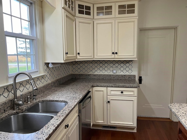 kitchen with sink, stainless steel dishwasher, dark hardwood / wood-style floors, decorative backsplash, and light stone countertops