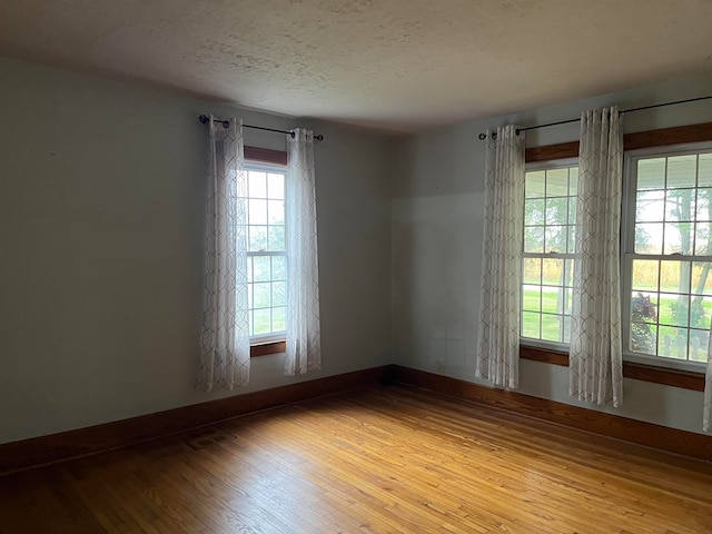 spare room featuring hardwood / wood-style floors, a healthy amount of sunlight, and a textured ceiling