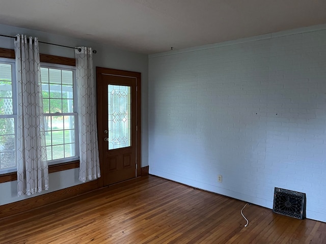 foyer entrance with dark hardwood / wood-style floors and brick wall