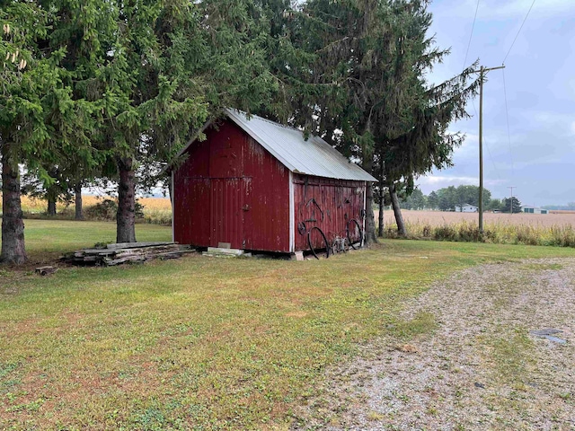 view of outbuilding with a lawn and a rural view