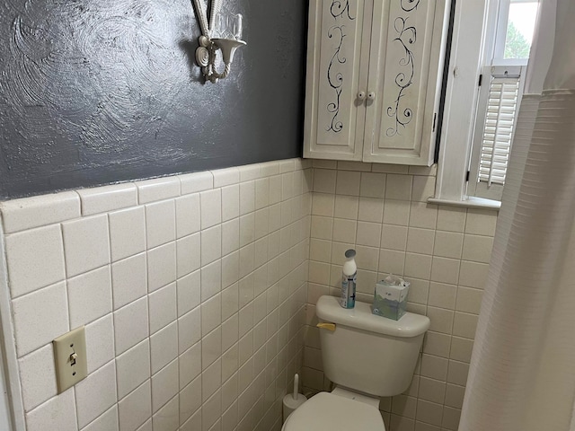 bathroom with toilet and tile walls