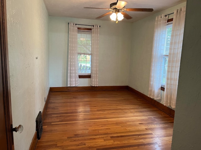 empty room featuring plenty of natural light, ceiling fan, and light wood-type flooring