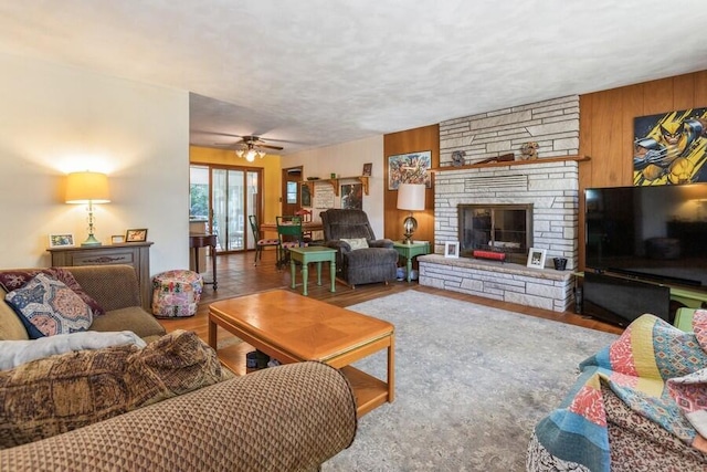 living room with wood walls, a fireplace, ceiling fan, and hardwood / wood-style floors