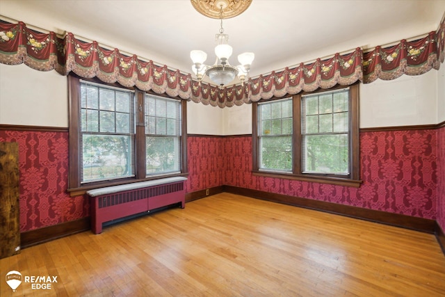 unfurnished room featuring radiator, a chandelier, and wood-type flooring