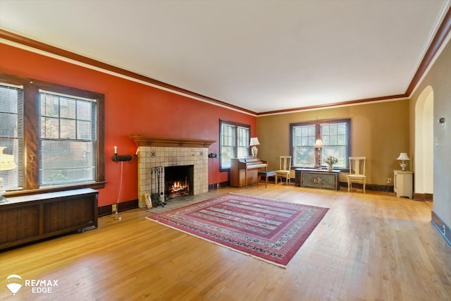 living room with a tile fireplace, light wood-type flooring, radiator, and ornamental molding