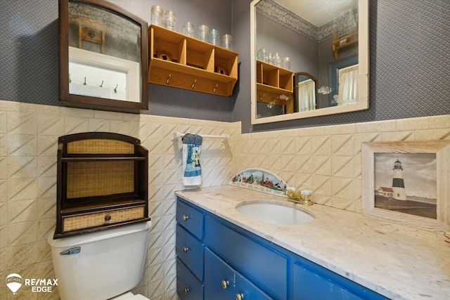 bathroom with vanity, tile walls, and toilet