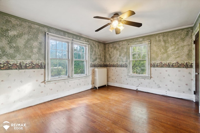 unfurnished room with hardwood / wood-style flooring, radiator, ornamental molding, and ceiling fan