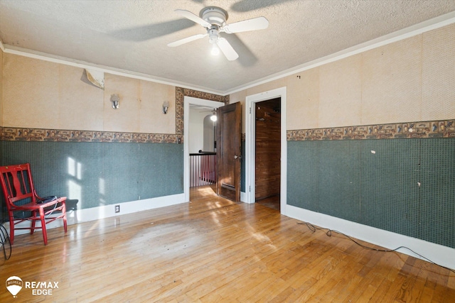 spare room featuring a textured ceiling, hardwood / wood-style flooring, ceiling fan, and ornamental molding