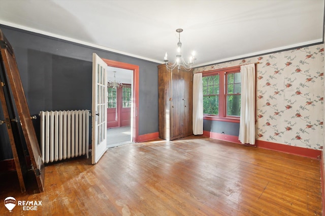 unfurnished dining area featuring radiator, crown molding, hardwood / wood-style floors, and a notable chandelier