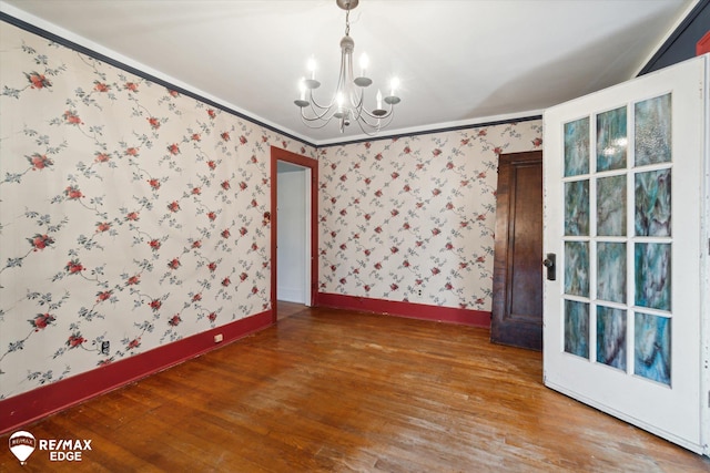 unfurnished room with a chandelier, hardwood / wood-style floors, and crown molding