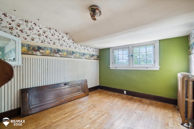 interior space with lofted ceiling, radiator heating unit, and light hardwood / wood-style flooring